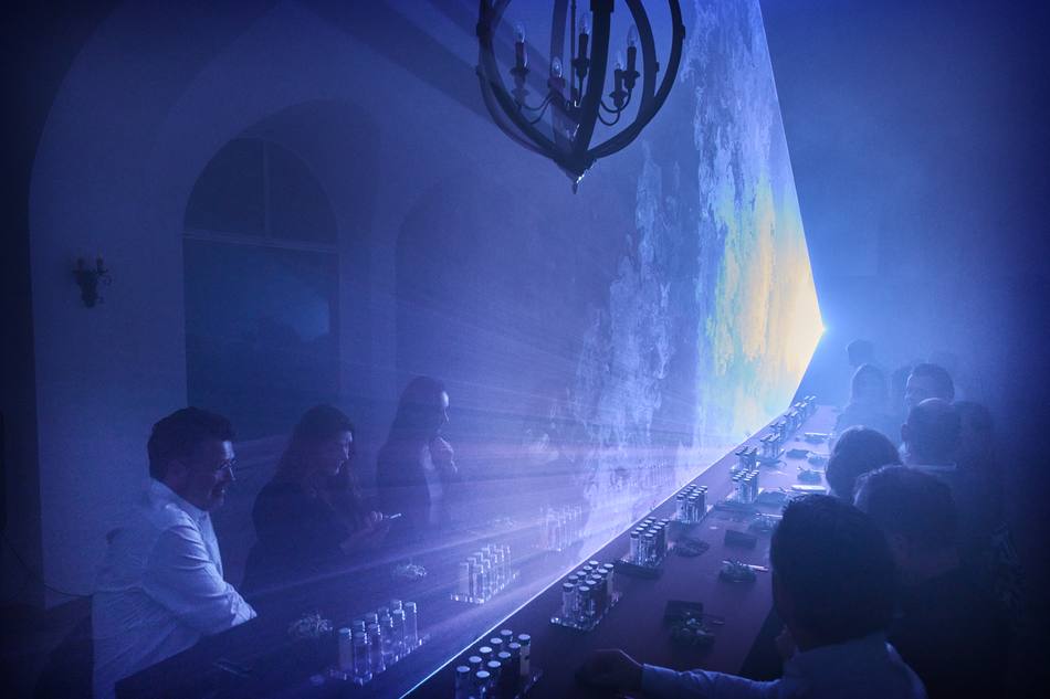 A projected surface filling the haze above the dinner table during a transition between courses